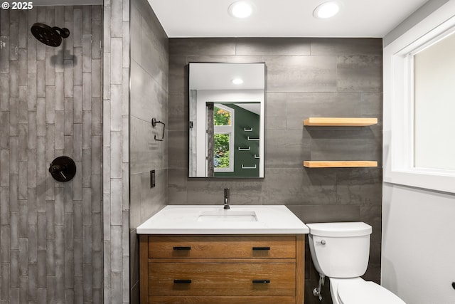 full bath featuring toilet, tiled shower, and vanity