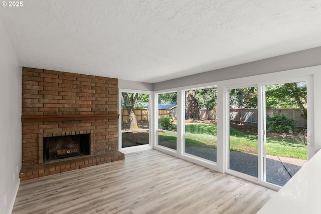 unfurnished living room featuring a fireplace, a textured ceiling, and wood finished floors