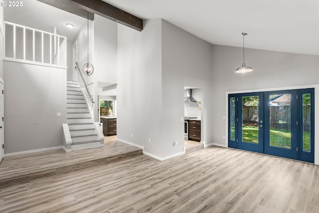 unfurnished living room featuring french doors, wood finished floors, a healthy amount of sunlight, and high vaulted ceiling
