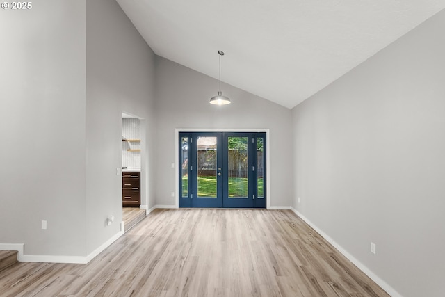 interior space featuring light wood-style floors, baseboards, high vaulted ceiling, and french doors