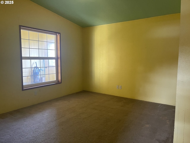 spare room with dark colored carpet and lofted ceiling