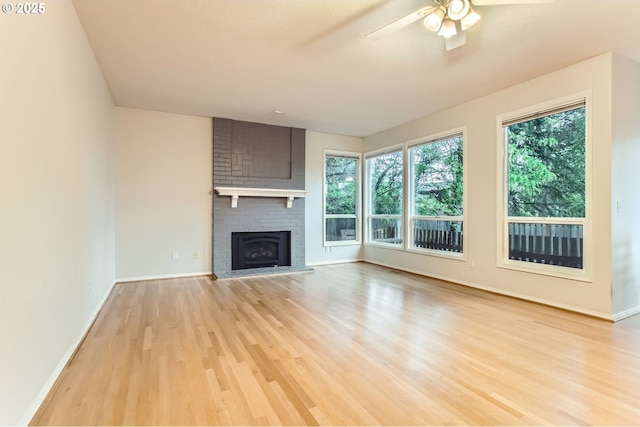 unfurnished living room with light wood finished floors, baseboards, a fireplace, and ceiling fan