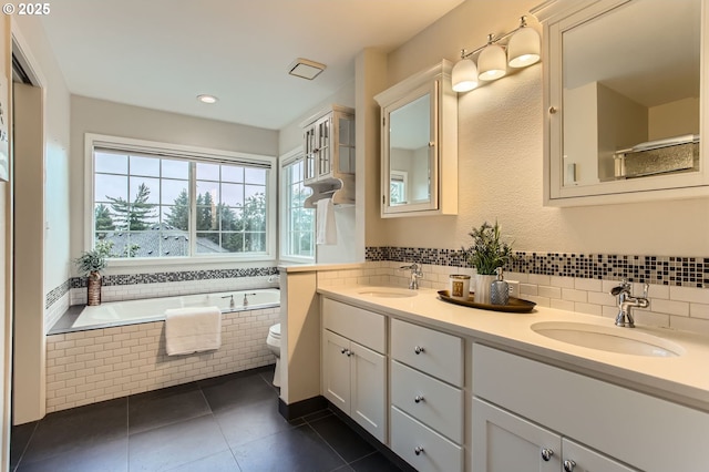 full bathroom with tile patterned flooring, a bath, double vanity, tasteful backsplash, and toilet