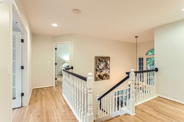 hallway with an upstairs landing, wood finished floors, recessed lighting, and baseboards