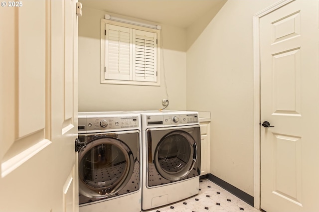 laundry area featuring separate washer and dryer, light floors, baseboards, and cabinet space