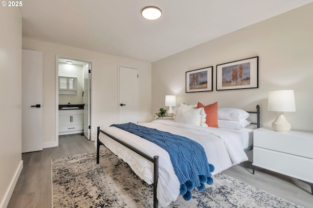 bedroom featuring connected bathroom, sink, and hardwood / wood-style floors