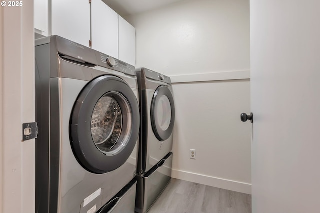 laundry room with cabinets, separate washer and dryer, and light wood-type flooring