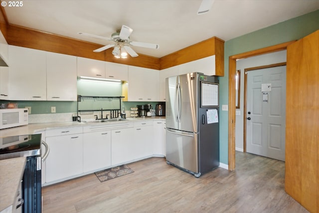 208 E 3rd St, Molalla, OR 97038 - kitchen featuring appliances with stainless steel finishes, a sink, ceiling fan, light wood-style flooring, and light countertops