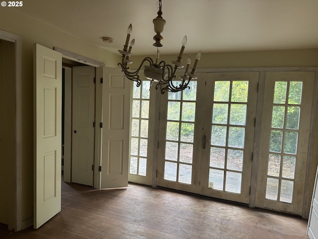 doorway to outside with hardwood / wood-style flooring, plenty of natural light, and a notable chandelier