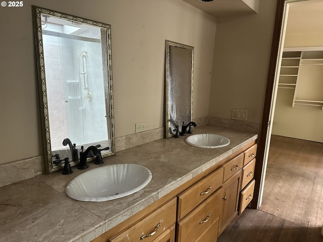 full bathroom featuring wood finished floors, a sink, and double vanity