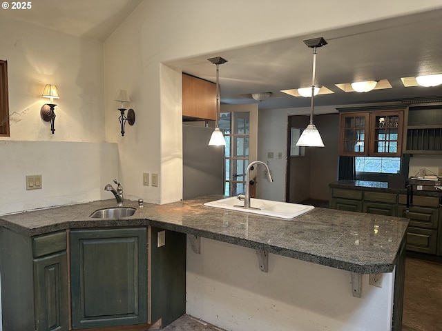 kitchen featuring a peninsula, dark countertops, and a sink