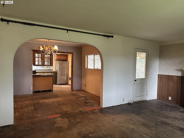 interior space with arched walkways, a wainscoted wall, and a notable chandelier