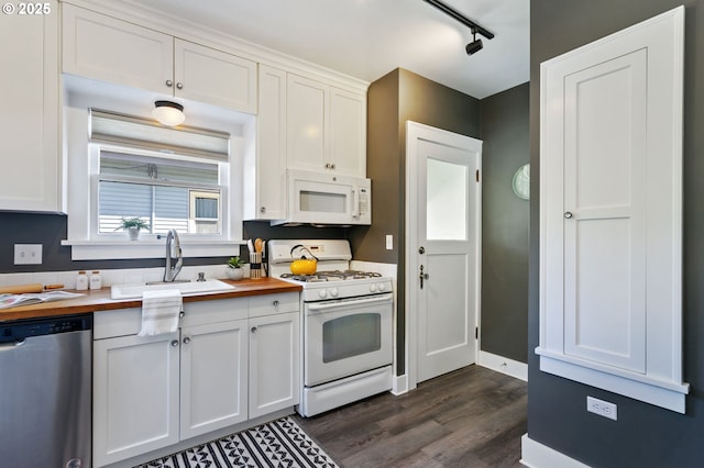 kitchen featuring white appliances, butcher block counters, a sink, dark wood finished floors, and white cabinetry