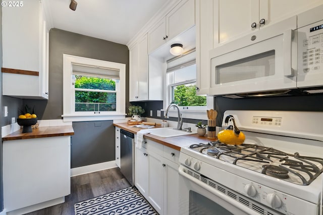 kitchen with white appliances, wooden counters, a sink, and healthy amount of natural light