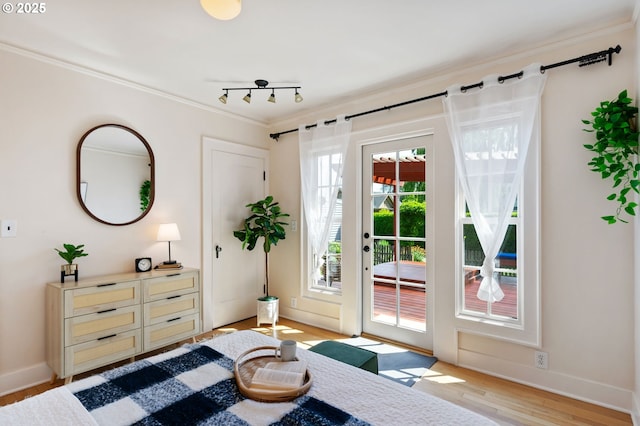 doorway to outside featuring crown molding, light wood finished floors, and baseboards