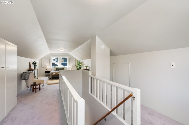 corridor featuring an upstairs landing, light colored carpet, and lofted ceiling