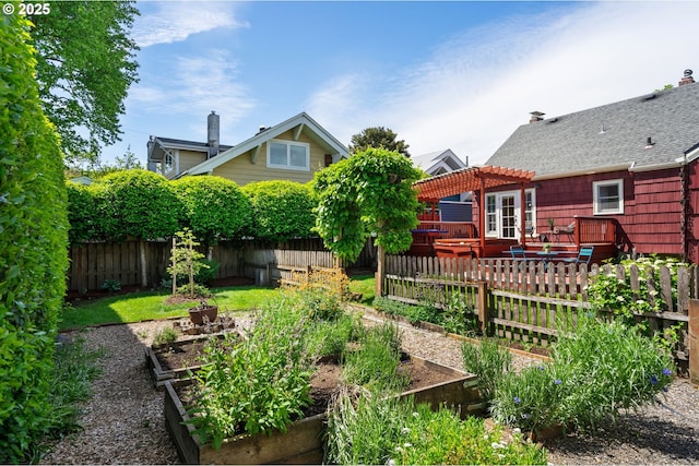 fenced backyard featuring a vegetable garden, a pergola, and a wooden deck