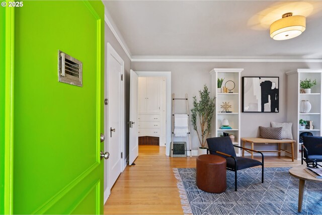 living area with light wood-type flooring and ornamental molding
