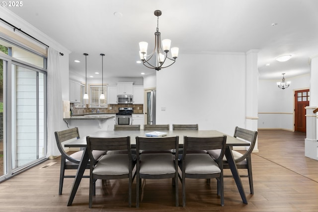 dining area featuring light hardwood / wood-style floors, crown molding, and a notable chandelier