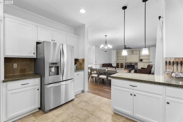 kitchen featuring ceiling fan with notable chandelier, white cabinetry, stainless steel refrigerator with ice dispenser, and decorative light fixtures