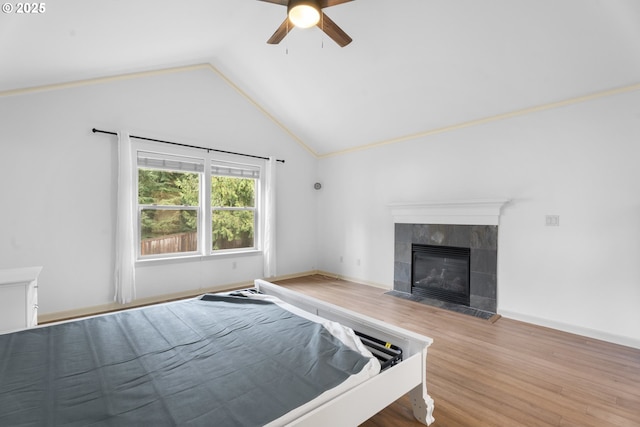 unfurnished bedroom featuring ceiling fan, a fireplace, wood-type flooring, and vaulted ceiling