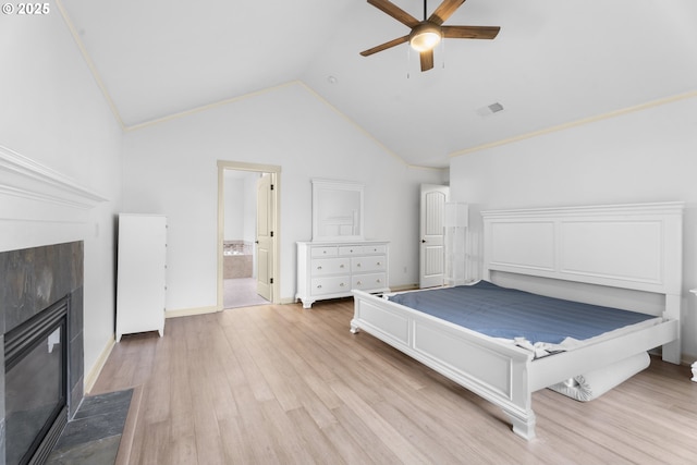 unfurnished bedroom with light wood-type flooring, ceiling fan, a tile fireplace, connected bathroom, and lofted ceiling