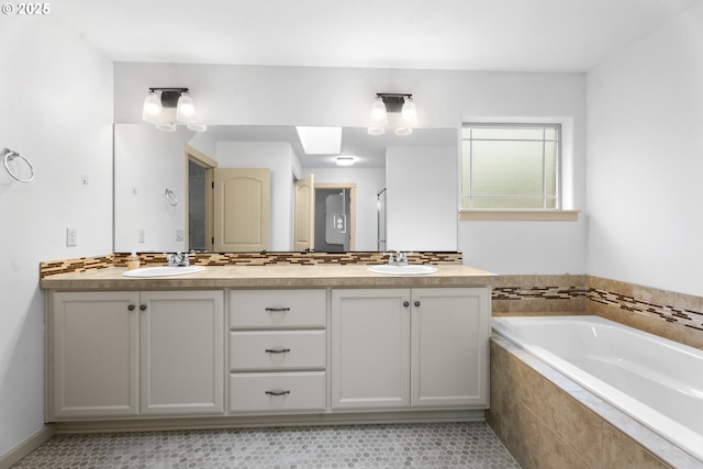 bathroom with tile patterned floors, vanity, backsplash, and tiled bath