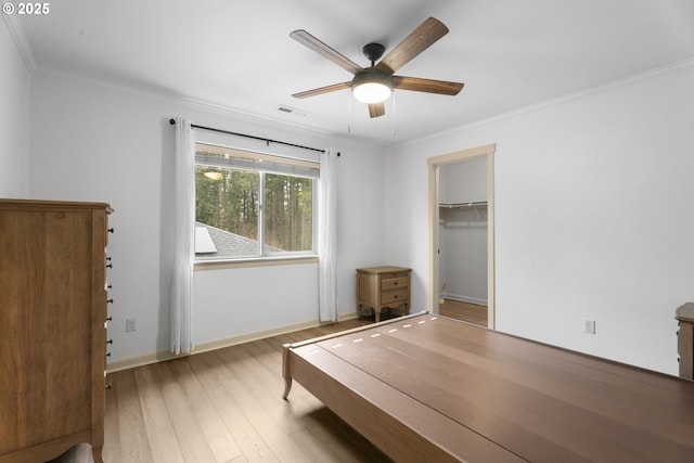 unfurnished bedroom featuring ceiling fan, light hardwood / wood-style flooring, a spacious closet, and ornamental molding