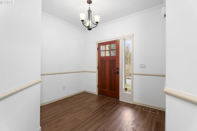 entryway featuring ornamental molding, dark wood-type flooring, and a notable chandelier