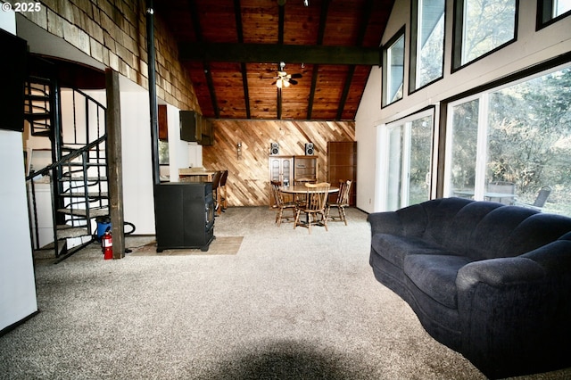 carpeted living room featuring wood ceiling, ceiling fan, beam ceiling, high vaulted ceiling, and wood walls