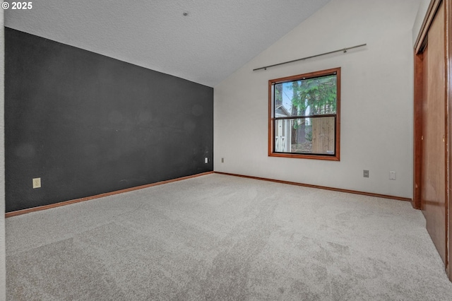 carpeted empty room featuring lofted ceiling and a textured ceiling