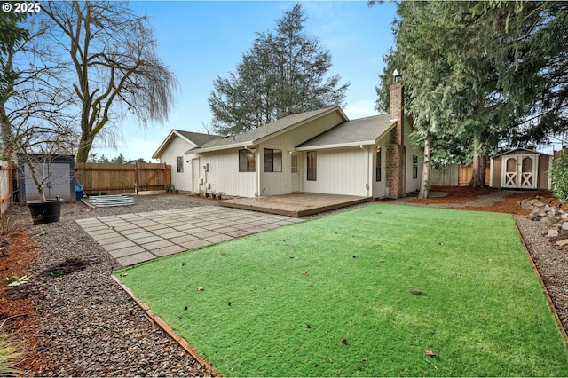 rear view of property with a storage shed, a deck, a patio area, and a lawn