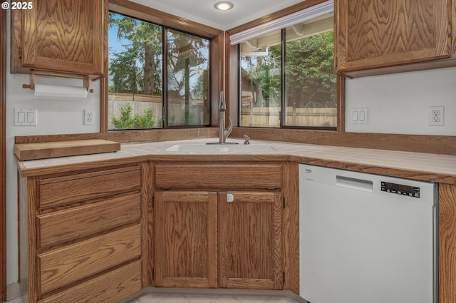 kitchen with tile counters, white dishwasher, and sink