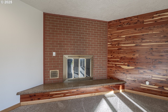 interior details with a fireplace, wooden walls, a textured ceiling, and carpet