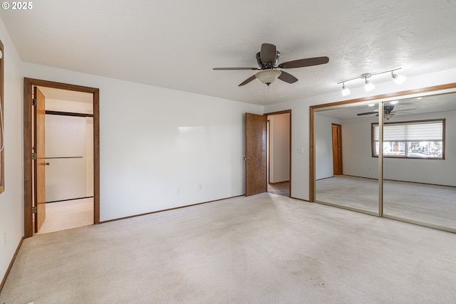 unfurnished bedroom featuring ceiling fan, light colored carpet, a closet, and a textured ceiling