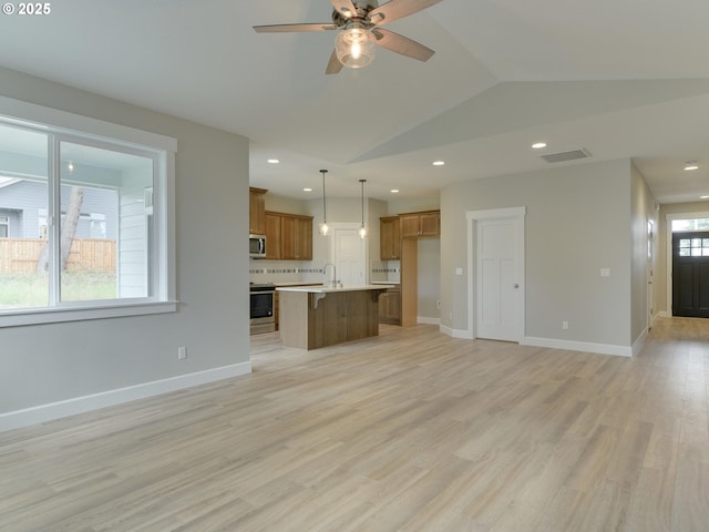 unfurnished living room with a healthy amount of sunlight, light hardwood / wood-style floors, lofted ceiling, and sink