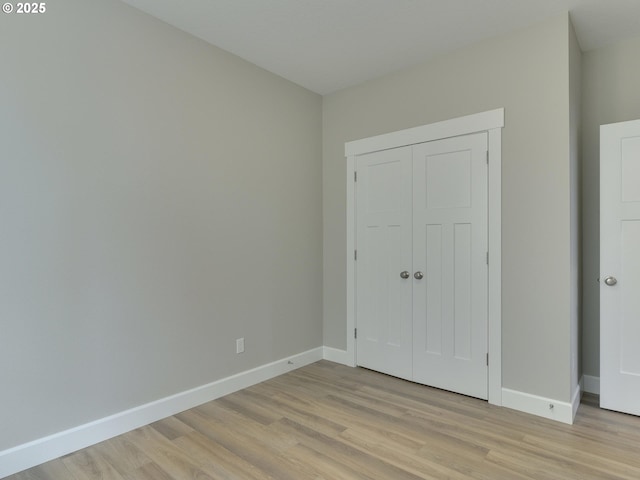 unfurnished bedroom with light wood-type flooring and a closet