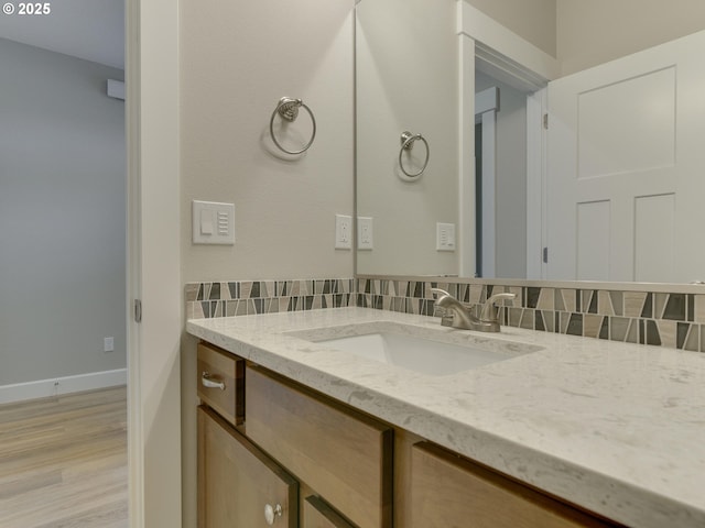 bathroom featuring decorative backsplash, vanity, wood finished floors, and baseboards