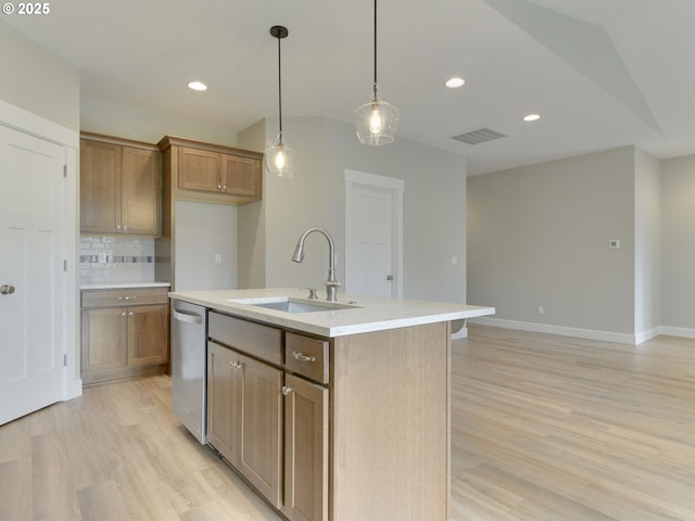 kitchen with tasteful backsplash, stainless steel dishwasher, sink, hanging light fixtures, and an island with sink