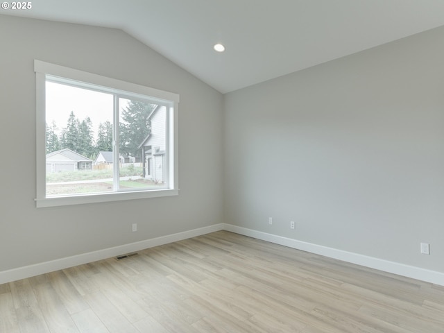 spare room featuring light hardwood / wood-style floors and vaulted ceiling