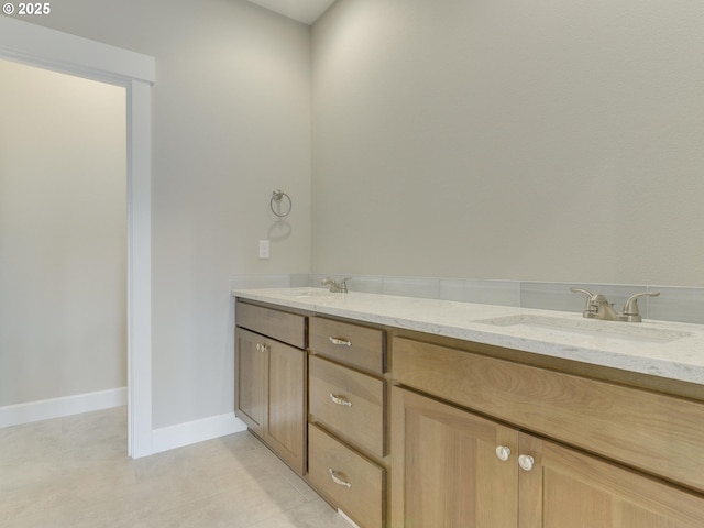 bathroom featuring double vanity, a sink, tile patterned flooring, and baseboards