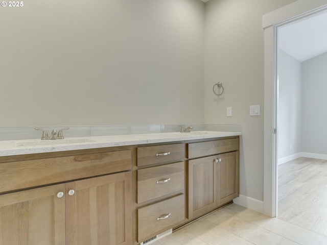 bathroom with a sink, baseboards, double vanity, and tile patterned flooring