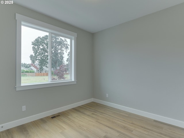 unfurnished room featuring visible vents, light wood-style flooring, and baseboards