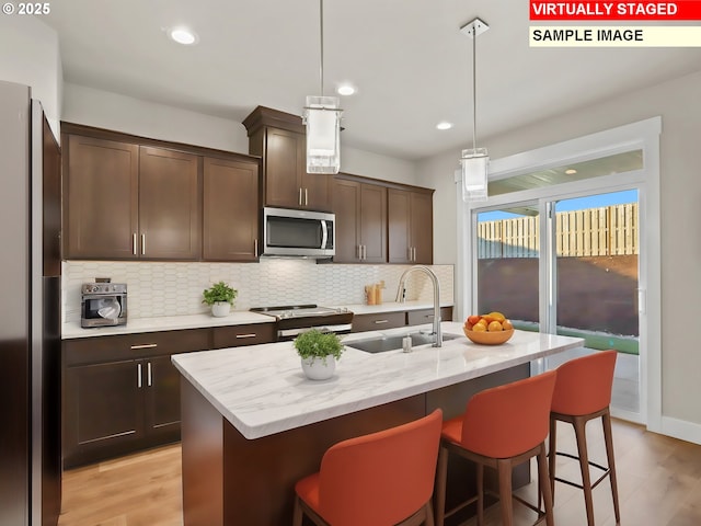 kitchen featuring a sink, a breakfast bar, dark brown cabinetry, stainless steel appliances, and backsplash