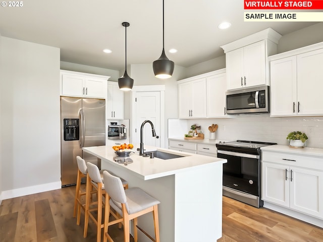 kitchen featuring light wood-style flooring, tasteful backsplash, appliances with stainless steel finishes, and a sink