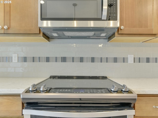 kitchen featuring light stone countertops, backsplash, and appliances with stainless steel finishes