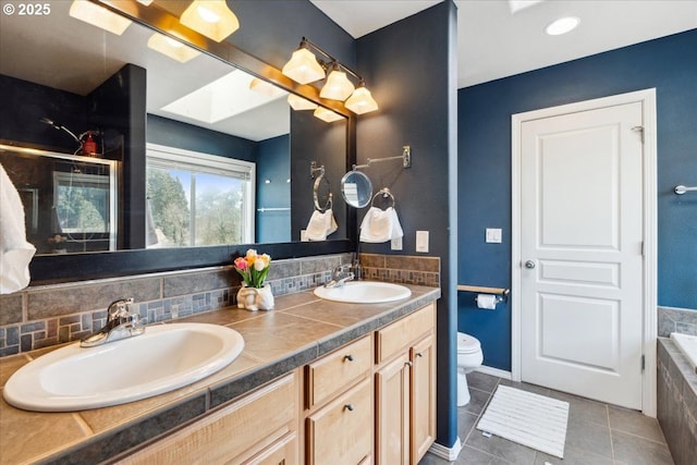 bathroom with double vanity, toilet, tasteful backsplash, and a sink