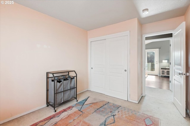 bedroom with a closet, baseboards, and light carpet