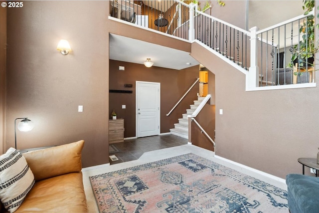 tiled entrance foyer with stairway, baseboards, and a towering ceiling