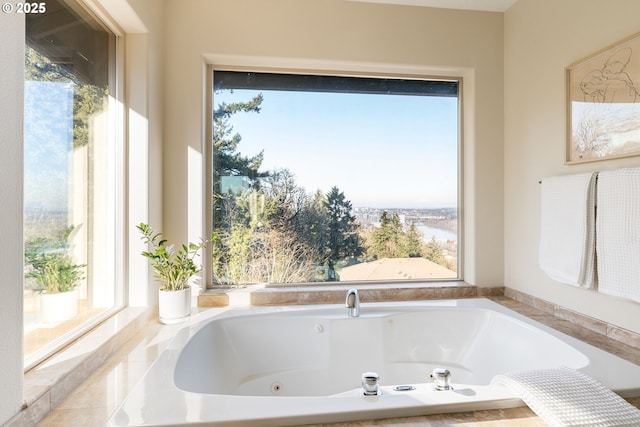 bathroom with tiled tub, a water view, and a wealth of natural light